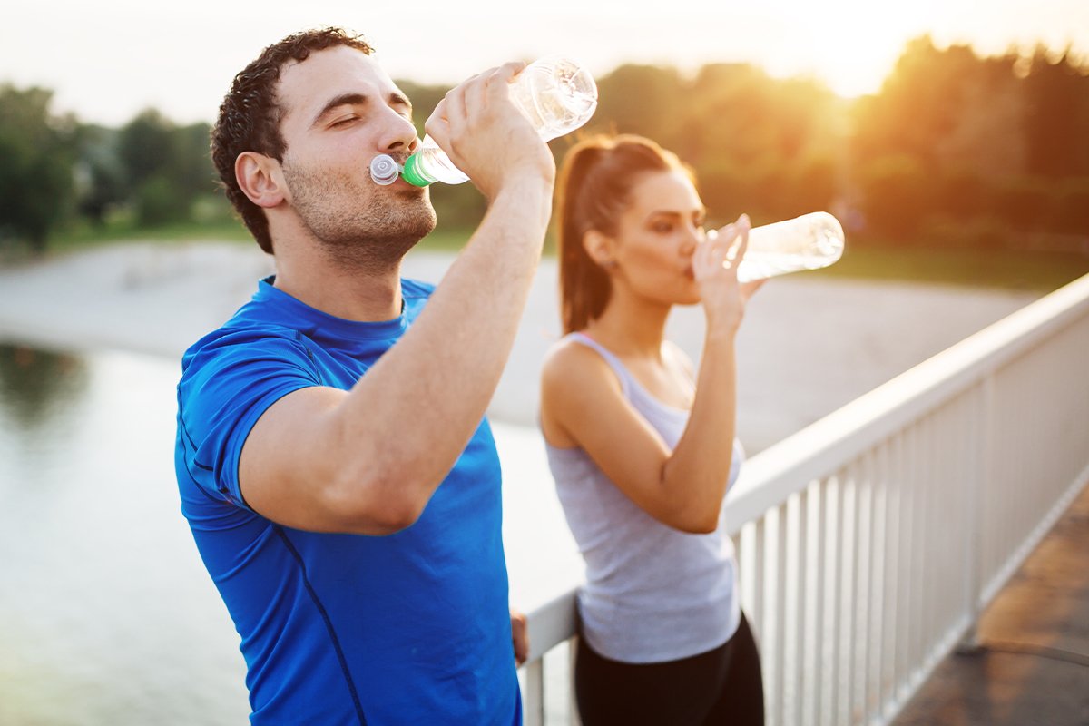 due persone che bevono acqua durante un allenamento